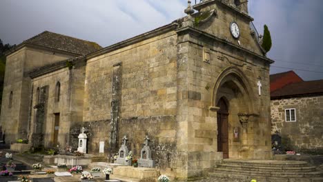 side angle tilt up establishes bell tower and clock at front of santa maria de punxin in ourense galicia spain