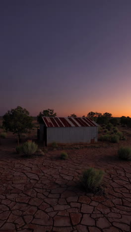corrugated iron shed in a dry outback landscape at dusk
