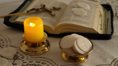 communion hosts lit candle and holy bible cross with jesus