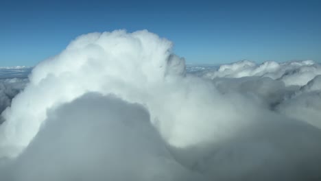 pilot’s pov fpv flying through the top of a stormy cloud. immersive view from cockpit while overflying a sea of white clouds. daylight, blue sky. 4k 60fps