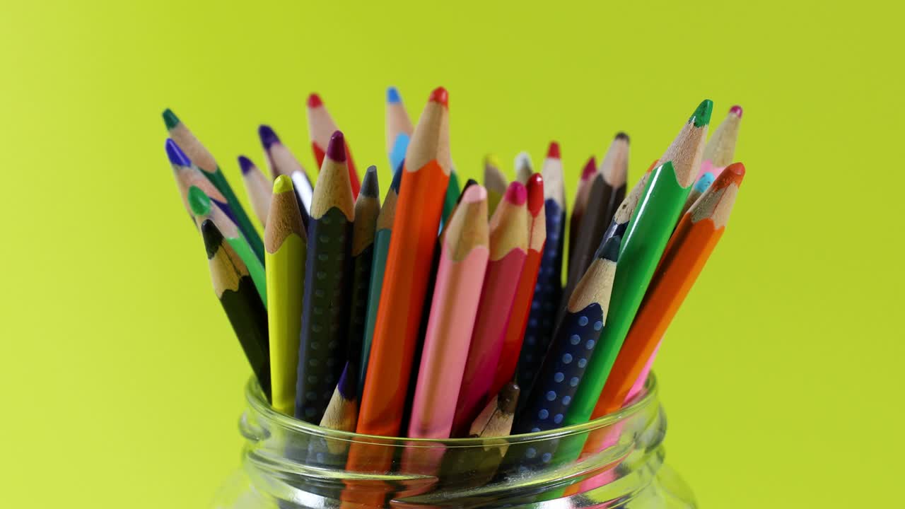 lápices de colores en frasco girando sobre un fondo amarillo. bucle sin costuras