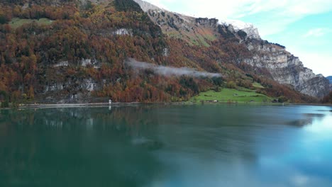 Slow-forward-pan-shot-of-a-cold-lake-and-high-mountain-summits-with-alpine-forest-of-pine-trees