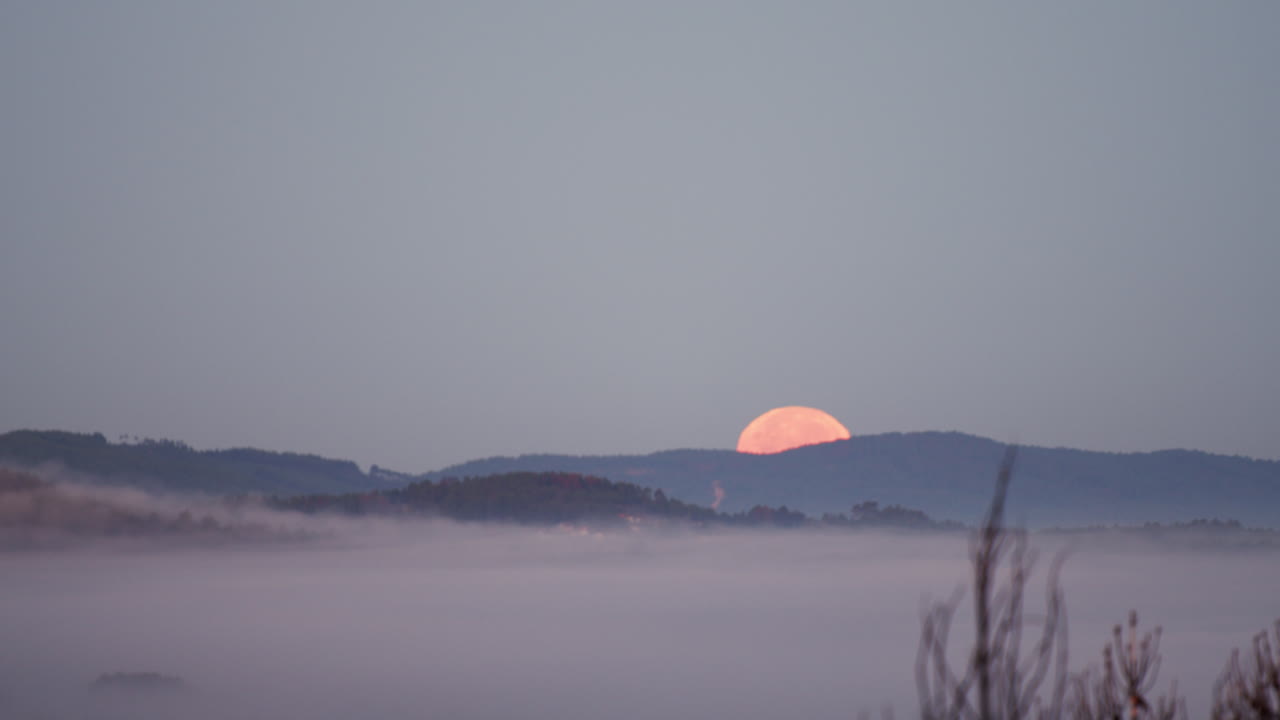 산 언덕 뒤에 숨어있는 주황색 달