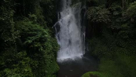 a powerful waterfall in the depths of balinese jungle on an overcast afternoon, aerial