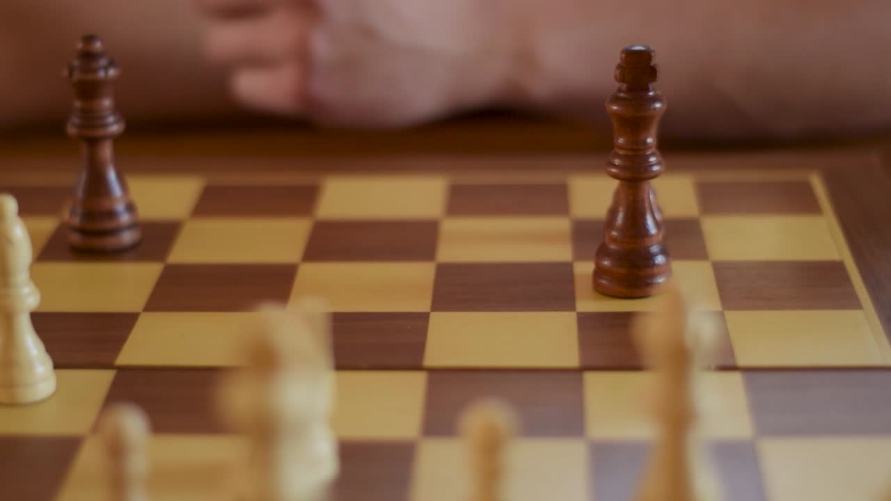 Close up of opponent drops the king on a wooden chessboard. Checkmate.