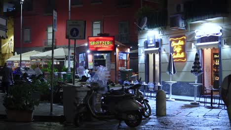 people walking by a lit street cafe