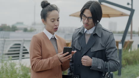 business people discussing on smartphone outside