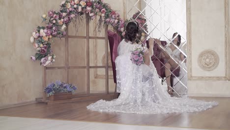 bride-with-long-lacy-train-by-flower-arch-backside-view