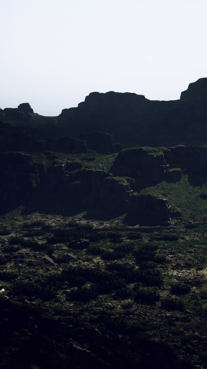 Mountain landscape viewed at dusk with dramatic shadows and rocky terrain
