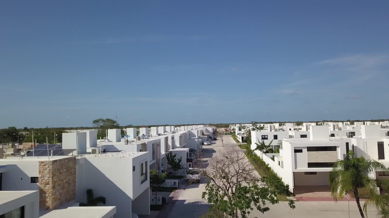 Toma aérea con dron en Mérida, México, de muchas casas blancas con una carretera nueva