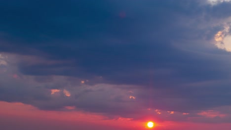 lapso de tiempo de una hermosa puesta de sol roja escénica sobre la ciudad con el sol brillando a través de las dramáticas nubes oscuras de tormenta, hora dorada, plano general