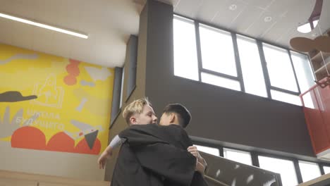 happy multiracial students throwing their mortarboards up in the air. they hug.