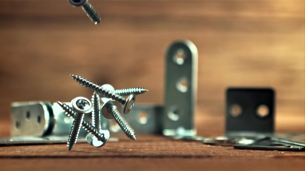 Metal Screws Falling in Slow Motion onto a Wooden Surface