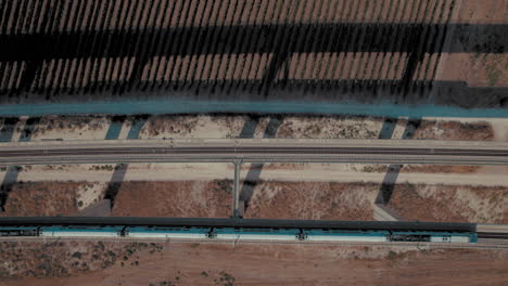 Aufnahme-Von-Oben-Nach-Unten-Von-2-Zügen,-Die-Nebeneinander-Auf-Einer-Massiven-Eisenbahnbrücke-über-Felder-Von-Weinbergen-Kreuzen