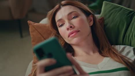 woman reading cellphone news feed lying couch close up. girl looking smartphone