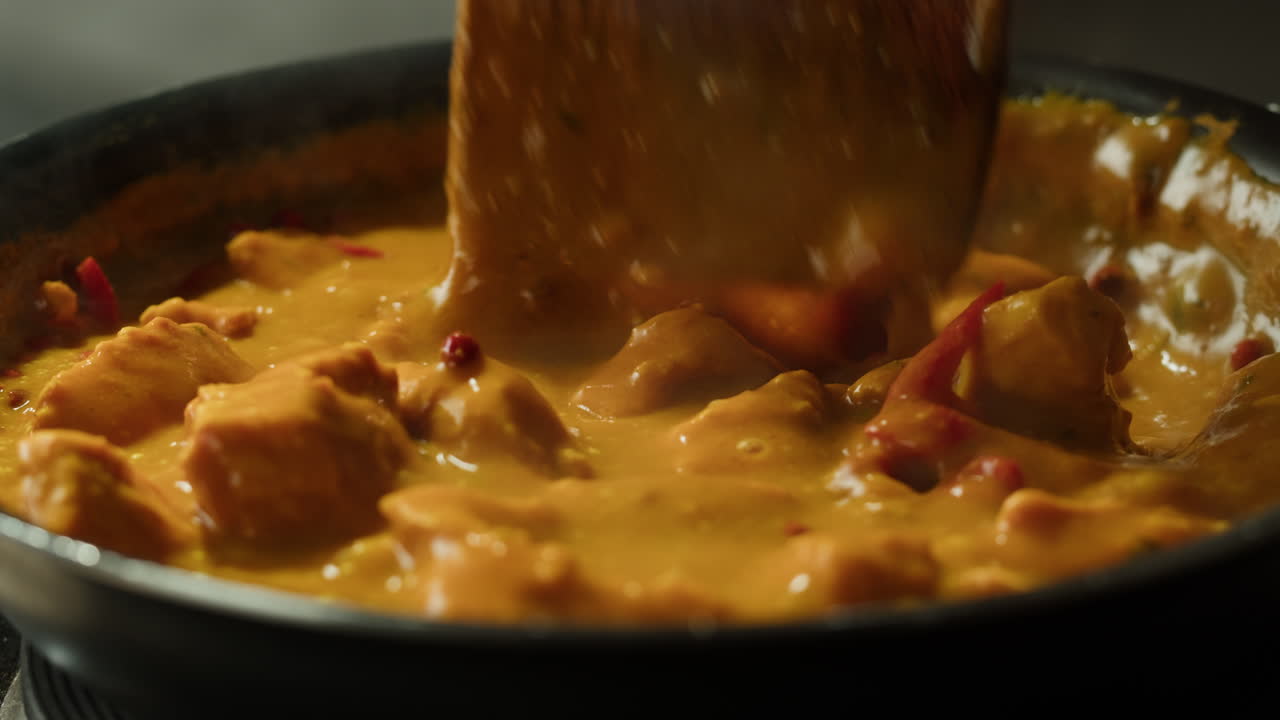 Yellow boiling sauce on pan close-up. Asian cuisine concept. Curry is a dish with a sauce seasoned with spices. Curries may contain fish, meat, poultry, or shellfish, either alone or in combination with vegetables. Others are vegetarian.