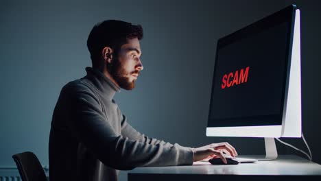 Worried office professional staring intently at computer screen revealing critical digital security warning in dimly lit workspace during late evening hours