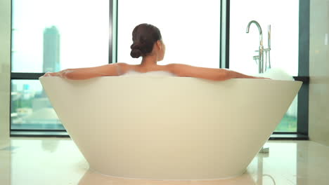 rear view of unrecognizable female sitting in luxurious bathtub