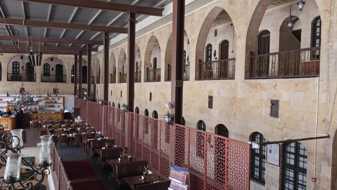 Una ripresa all'interno dell'Hotel Sirehan, un caravanserraglio restaurato dell'era ottomana a Gaziantep, Turchia, con archi in pietra, balconi in ferro e un caffè nel cortile.