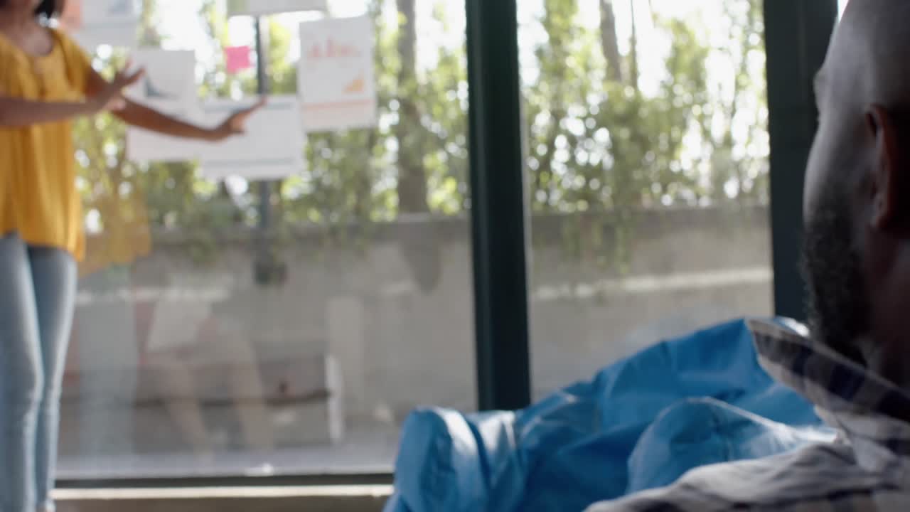 mujer de negocios afroamericana discutiendo con sus colegas sobre notas en la ventana de la oficina