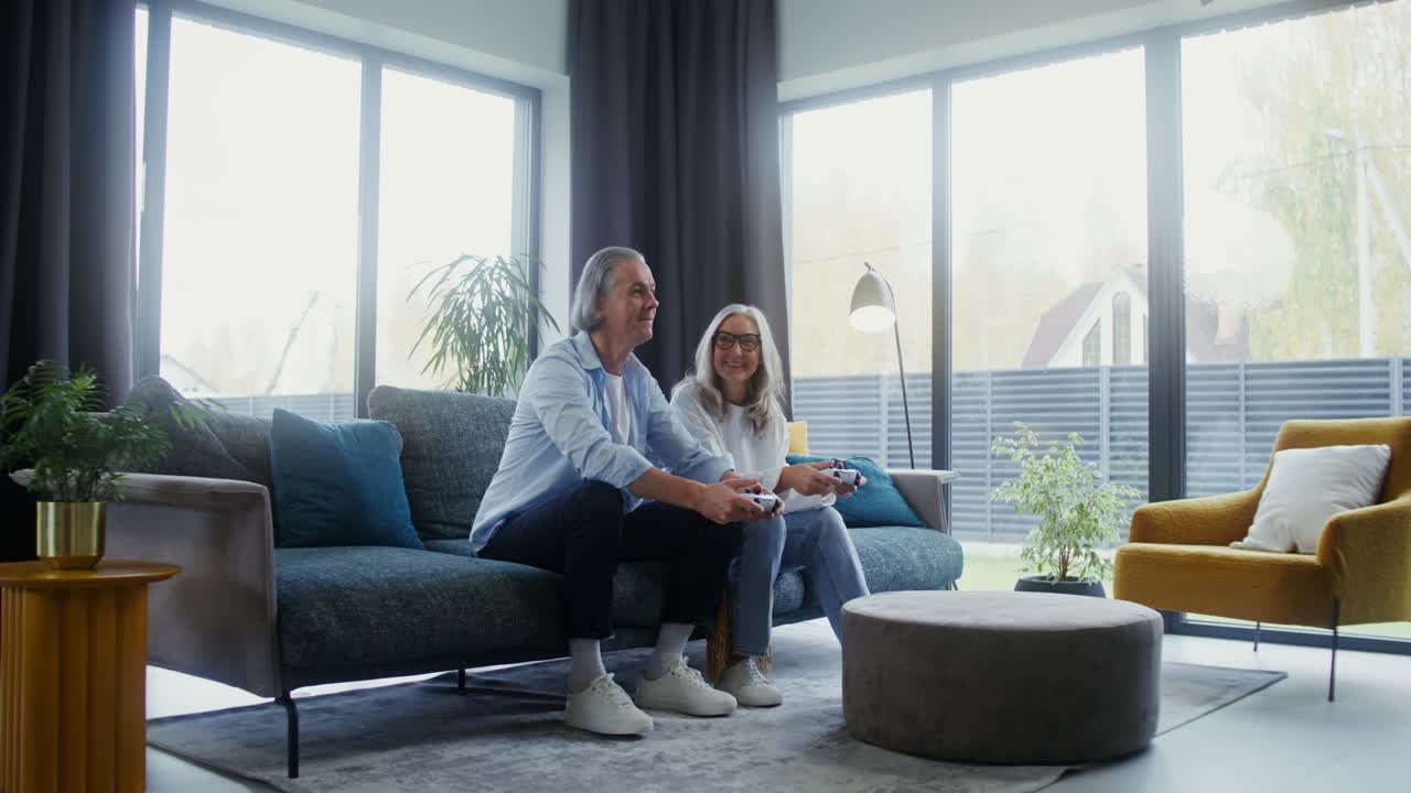 Senior couple playing video games in a modern living room