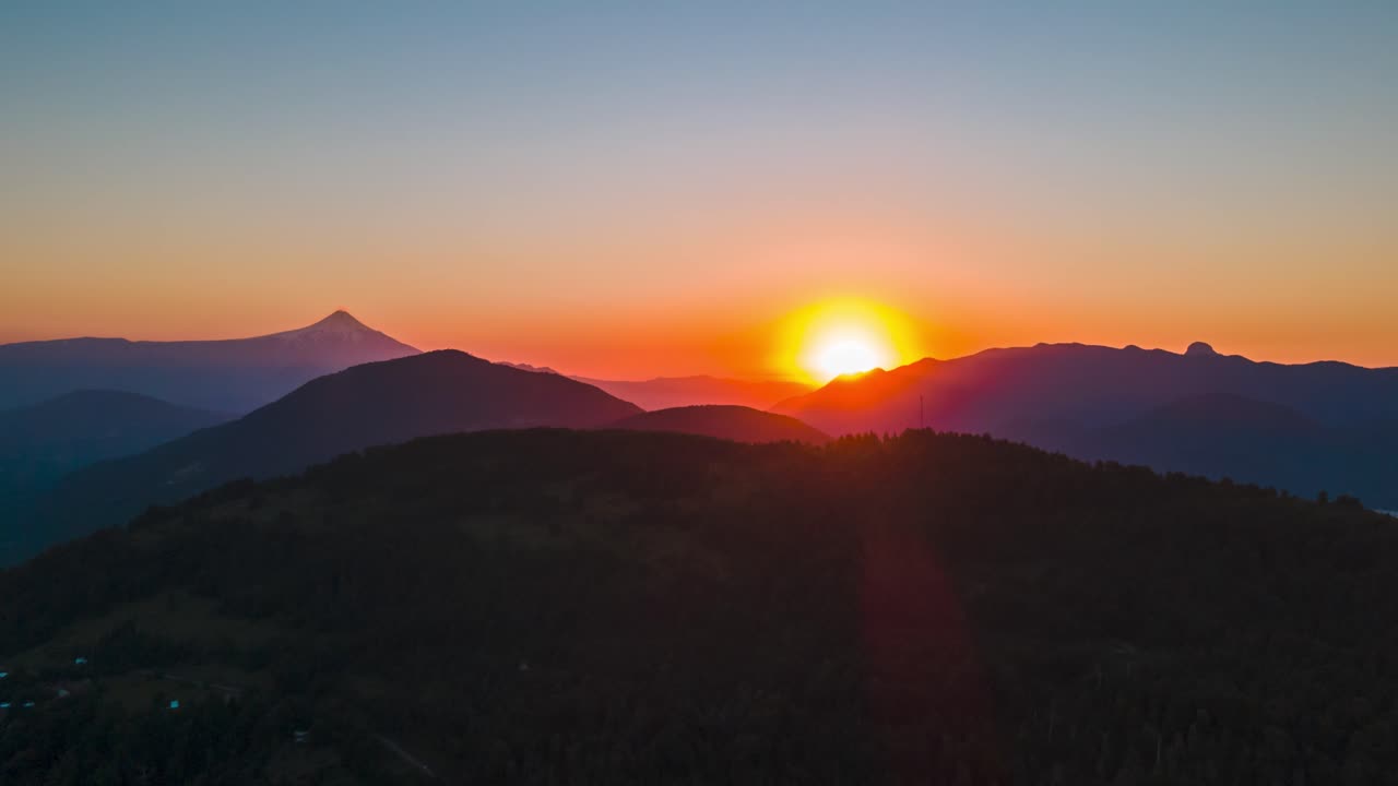 Truck left hyperlapse of Tinquilco lake surrounded by forest mountains and Villarrica volcano in background at sunset, Chile