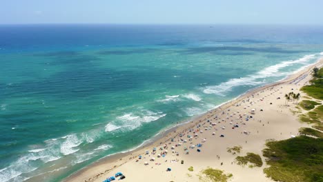 Aerial-drone-shot-flying-forward-past-the-Ritz-Carlton-toward-the-waves-crashing-on-the-beach-on-Singer-Island-while-clouds-make-shadows-on-the-water