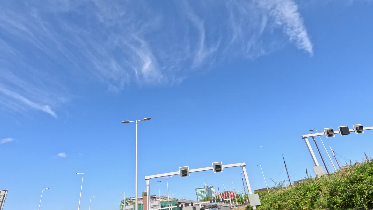 Vehicles drive toward a modern tunnel entrance under clear blue sky, daylight, smooth camera movement