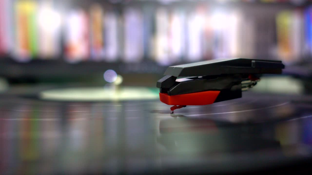 Primo piano 4K UHD del movimento di una puntina su un disco in vinile LP di un grammofono o un disco fonografico con etichetta verde. Disco album musicale nero a lunga durata da 12 pollici a 33 giri/min con solco a spirale. Riproduzione audio stereo.