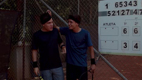 Two male athletes by the scoreboard after a tennis match