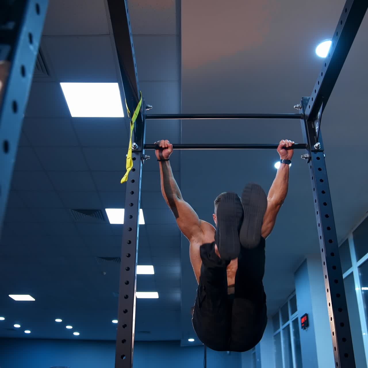 Shirtless man pulling up on horizontal bar