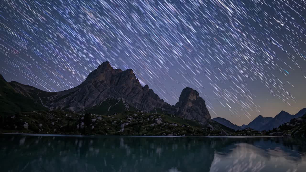 Time-lapse video of star trails over mountains, captured from a low-angle perspective