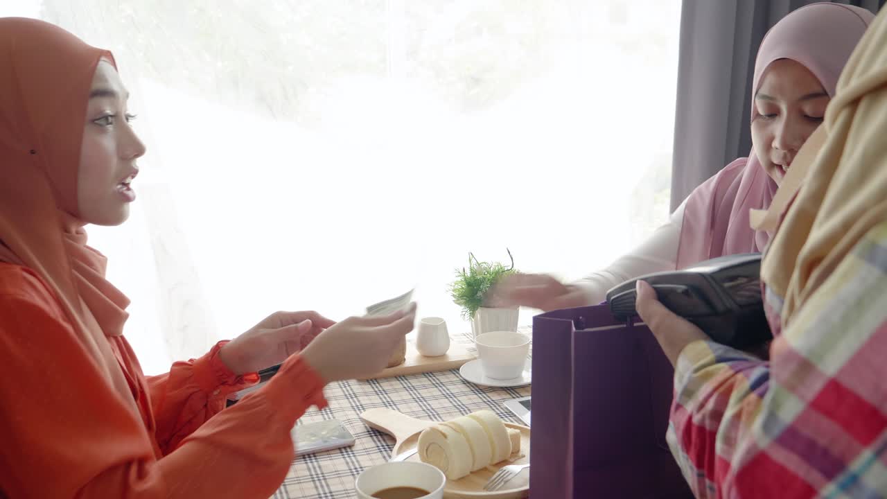 dos mujeres musulmanas comiendo y bebiendo en un restaurante usan escaneo y pago en reloj inteligente, concepto de tecnología de estilo de vida