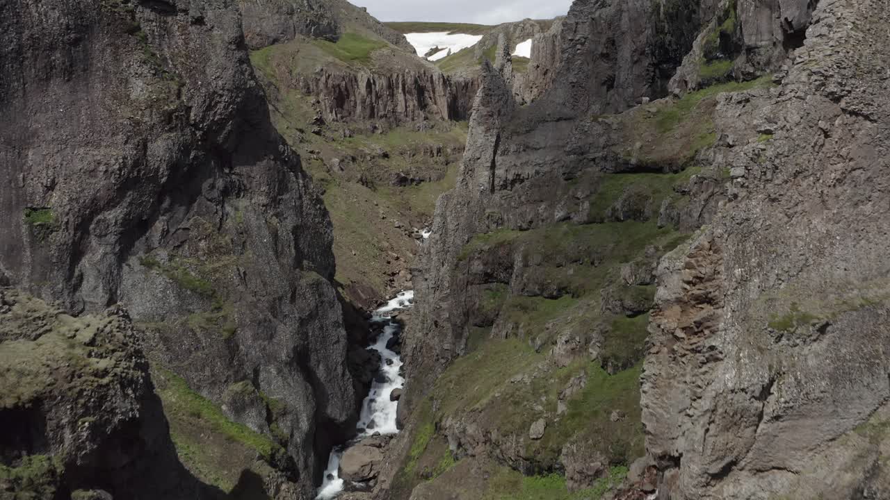 Aerial through otherworldly ravine with whitewater river in Icelandic landscape