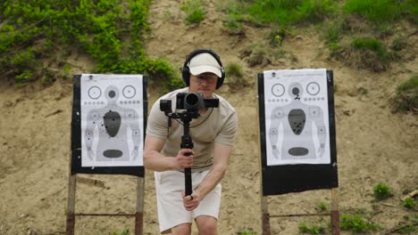 Cameraman-with-earmuffs-walk-near-Olesko-shooting-range-targets,-Czechia