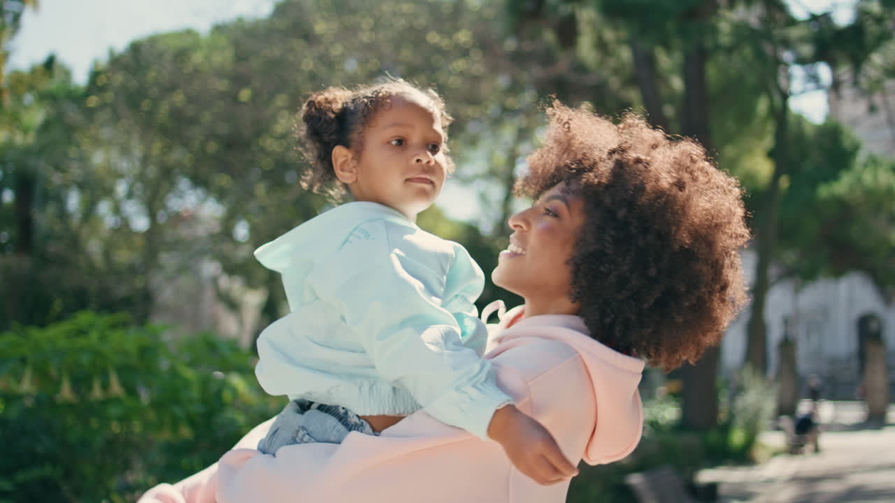 madre de pie hija linda en las manos disfrutando de la maternidad en el parque soleado de primer plano