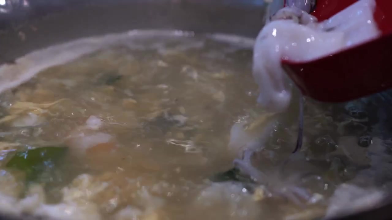 Primo piano di calamari freschi, fette di pesce e gamberi aggiunti a una pentola di shabu shabu fumante, che cattura il brodo bollente e i frutti di mare invitanti