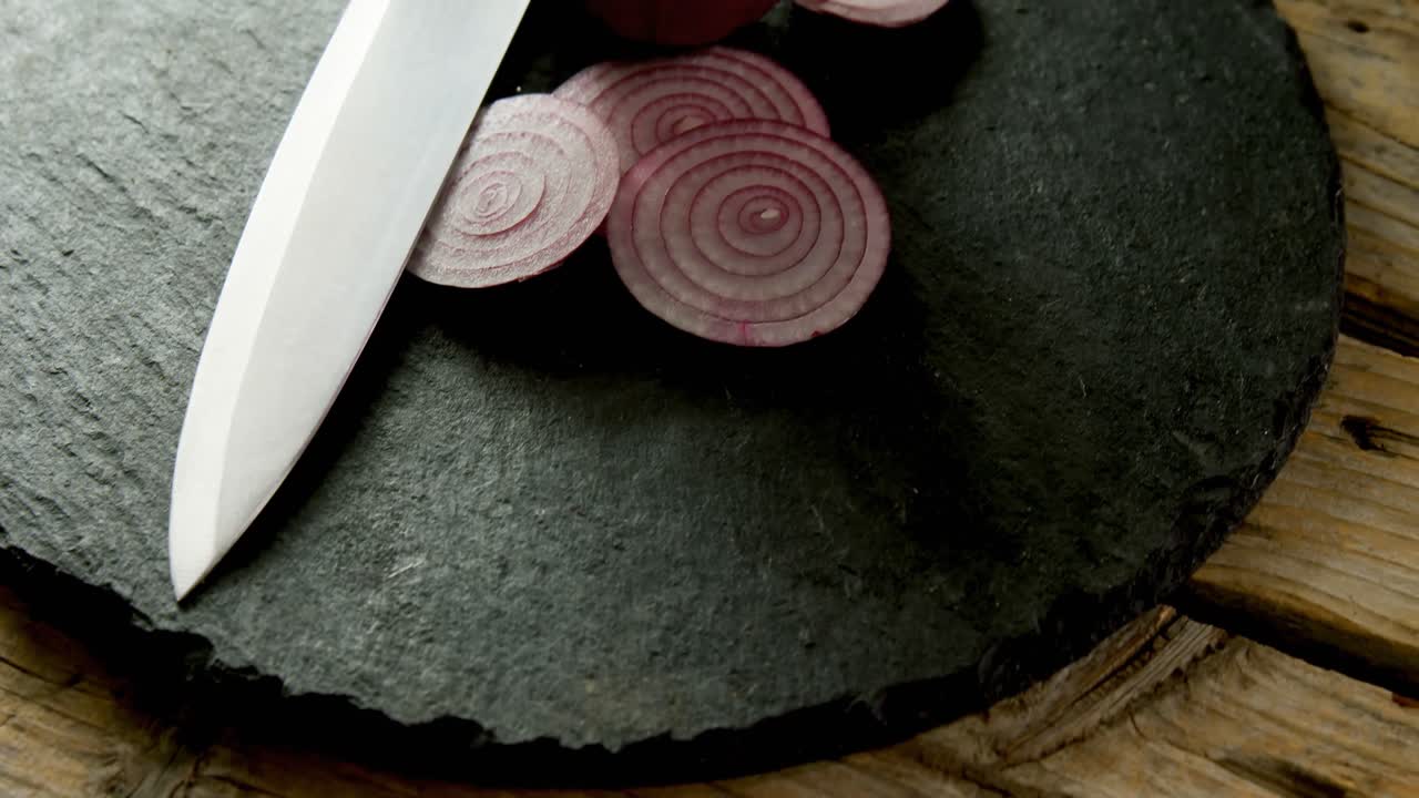 cebollas cortadas y cuchillo de cocina en tablero de hormigón 4k