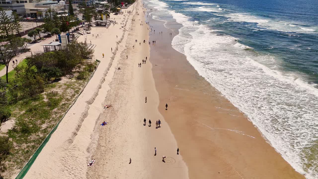 Aerial footage of Gold Coast beach showing waves, sand, and nearby cityscape under bright sunlight