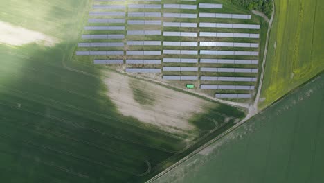 Aerial-revealing-shot-of-the-huge-photovoltaic-solar-power-plant-in-the-middle-of-the-farm-fields