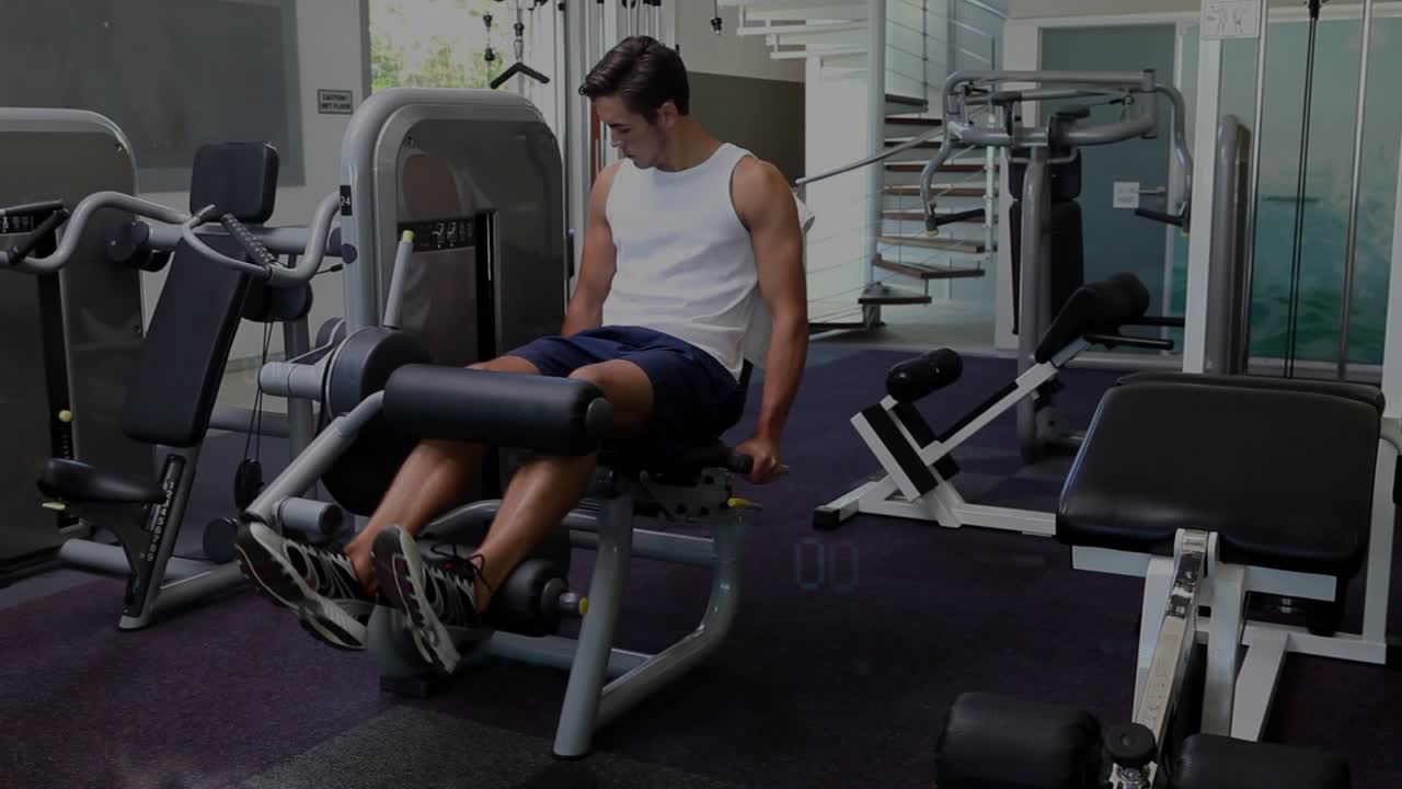 Man performing controlled leg extensions in gym, gripping handles and initiating reps for strength
