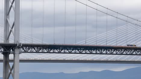 Autobús-Cruzando-El-Puente-De-Carretera-Con-Cruce-De-Queensferry-En-El-Fondo,-Close-up