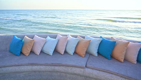 line of colorful pillow on a granitic bench in front of the sea