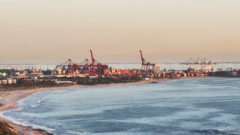 vista aérea del puerto de fremantle al atardecer con grúas, contenedores de carga y playa, perth, australia occidental