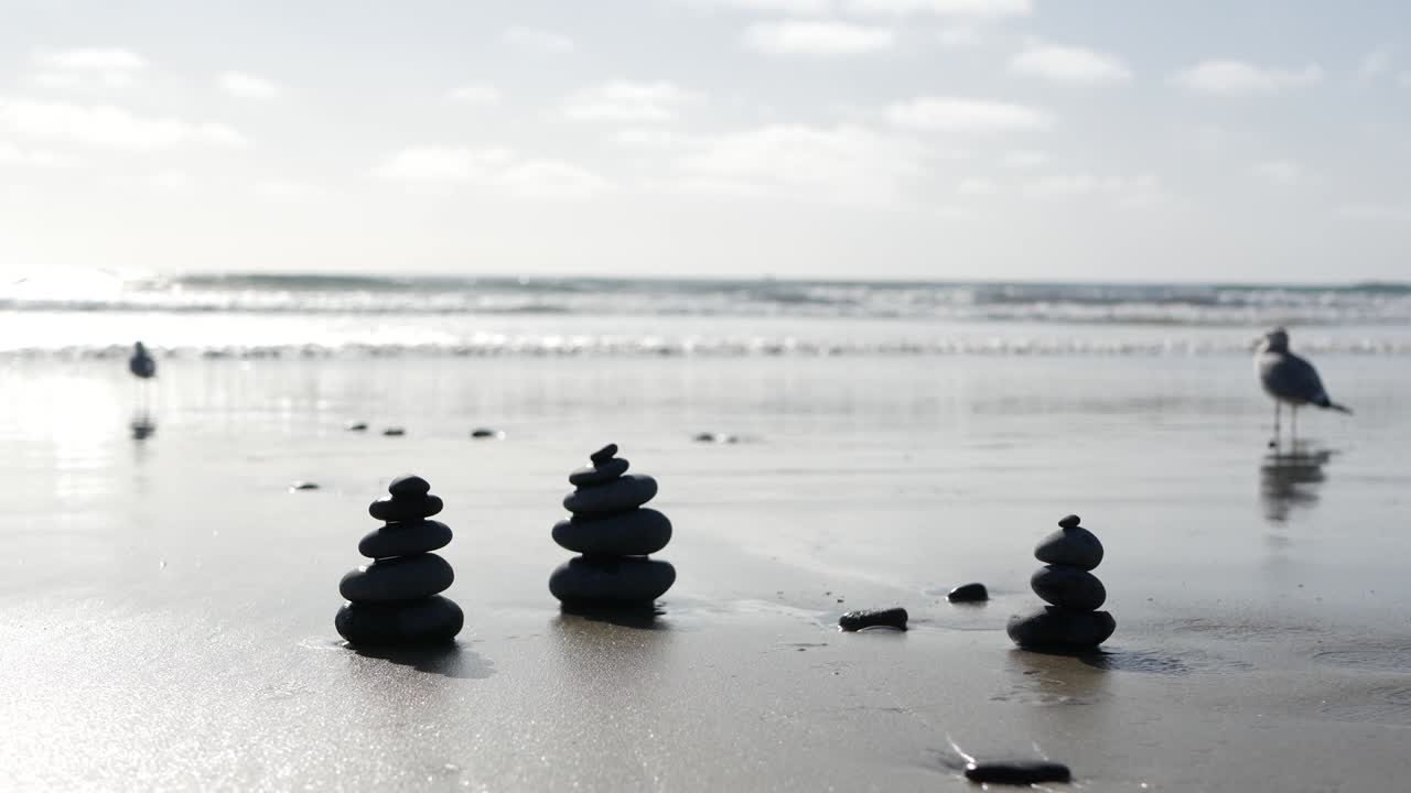 바다 해변에서 바위 균형을 잡고, 바물 파도에 의해 돌이 쌓여, 모래 해변에 있는 자갈의 피라미드.