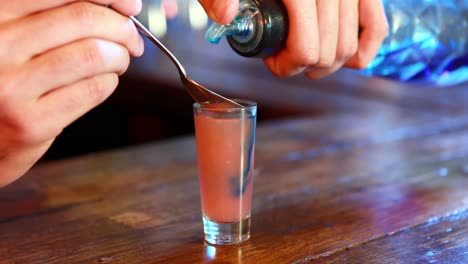 Barman-mixing-color-in-tequila-at-bar-counter