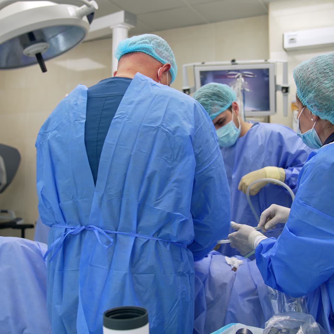 Medical team working in modern surgery room. Female nurse gives a transparent tube to the surgeons