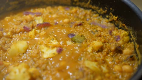 Primer-Plano-De-Curry-Indio-Dal-Cocinado-Con-Coliflor,-Garbanzos,-Cebollas-Y-Lentejas-Rojas-Junto-Con-Masala-Y-Cúrcuma-En-La-Cocina