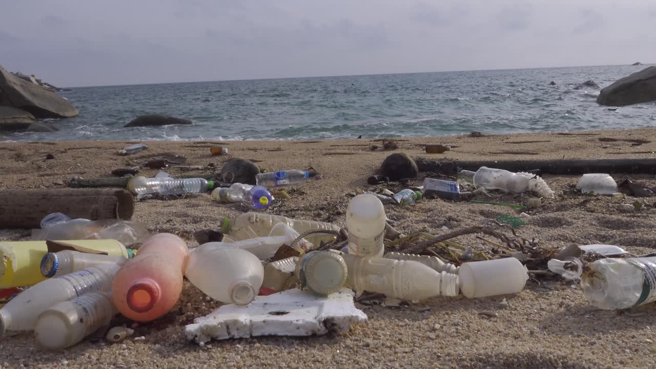 muchas botellas de plástico llenas de olas casi continuas frente a la playa, tiro estático 4k
