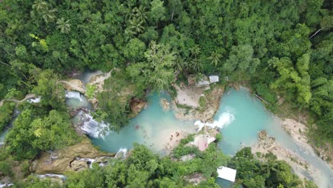 multi-tier kawasan falls with people canyoneering in waterfall blue pools amid lush tropical jungle